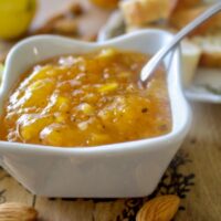 Apricot Jam with Ginger, Almonds and Mint in abowl with lemons, bread and almond on a table