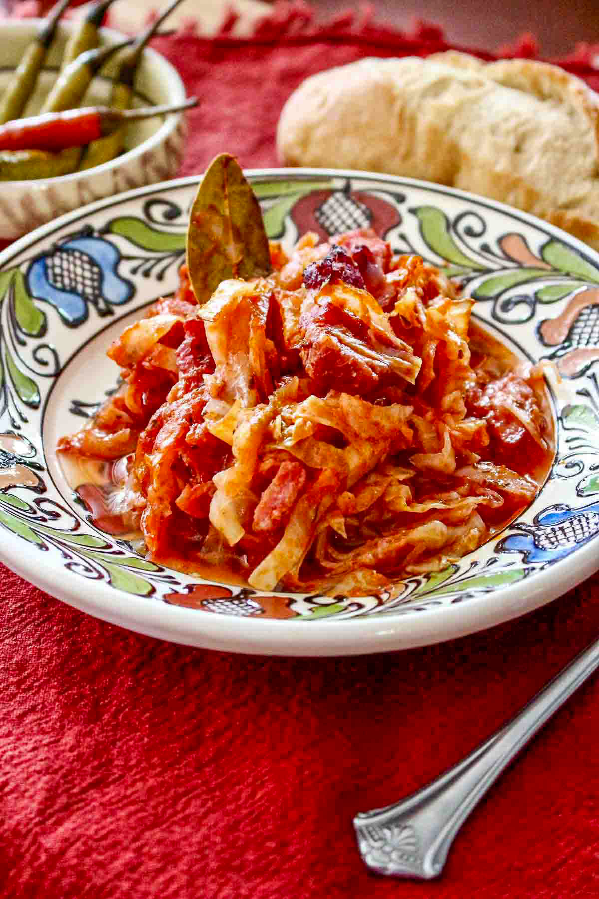 Cabbage and pork served on plate with bread and a fork.