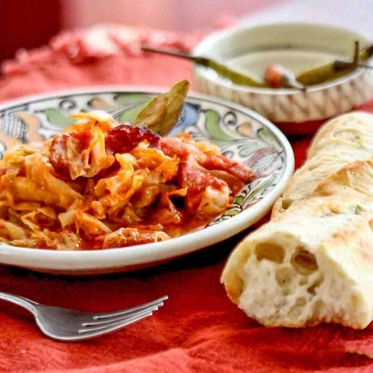 Cabbage with pork on a plate with fork and French baguette.