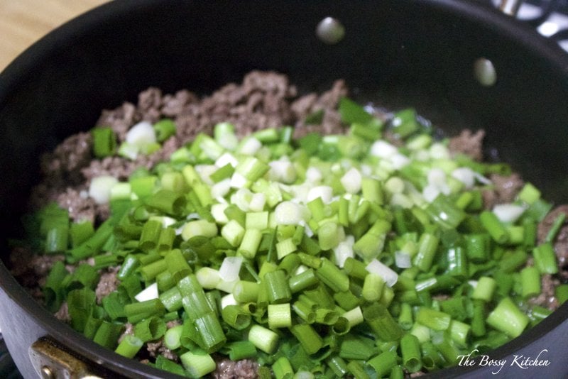 ground beef and green onions cooking in a pan