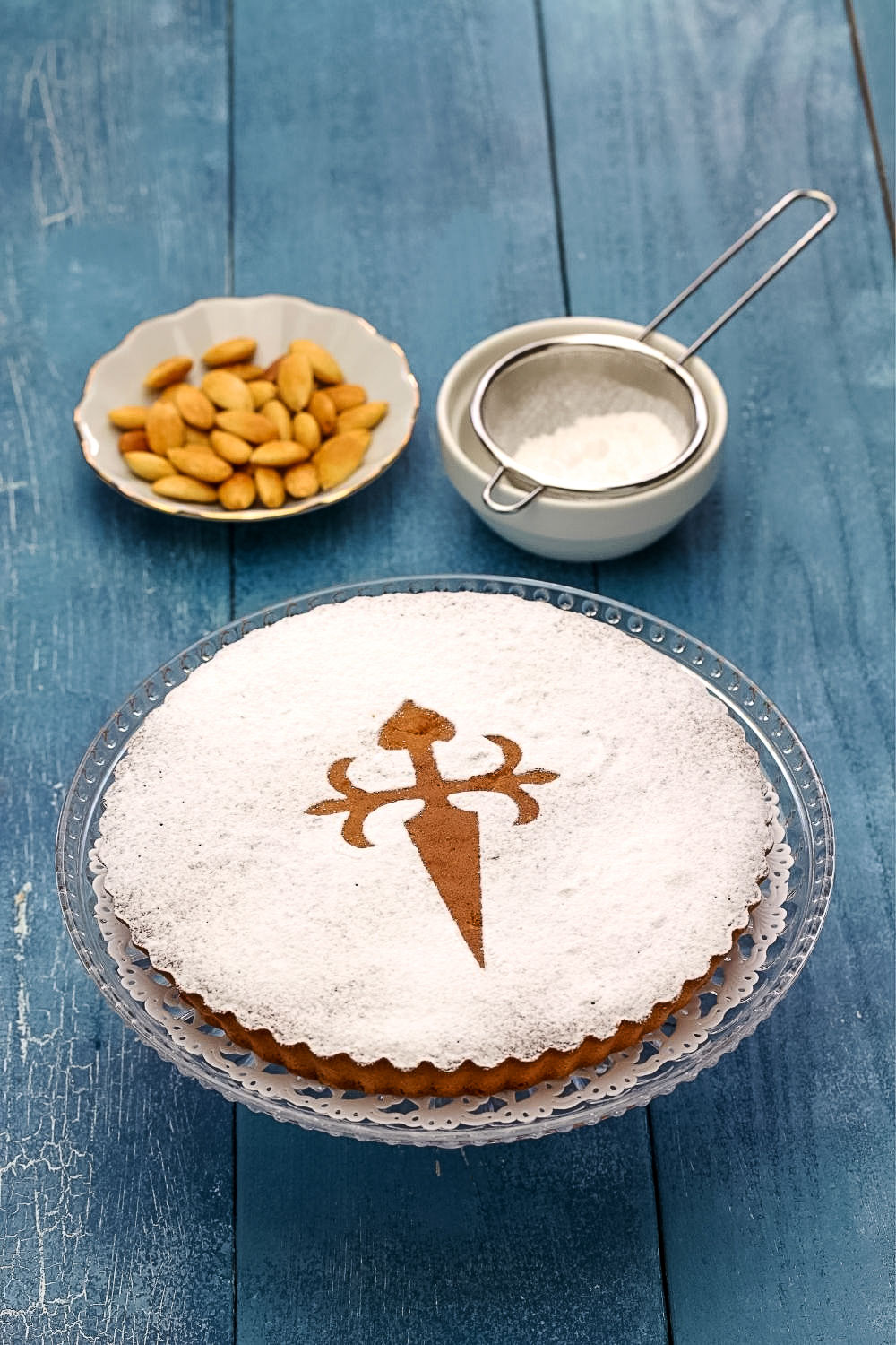 Spanish Almond Cake Recipe Tarta de Santiago33 A spanish almond cake on the table with a bowl of almonds and powdered sugar.