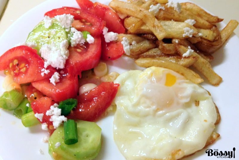 Tomato Cucumbers Feta Salad Recipe is a traditional authentic Romanian salad that can be made all year round. The salad doesn't use vinegar or lemon juice in the dressing, only sunflower oil, salt and pepper. Simple and delicious! Tomato Cucumbers Feta Salad served with fried egg and French fries on a white plate