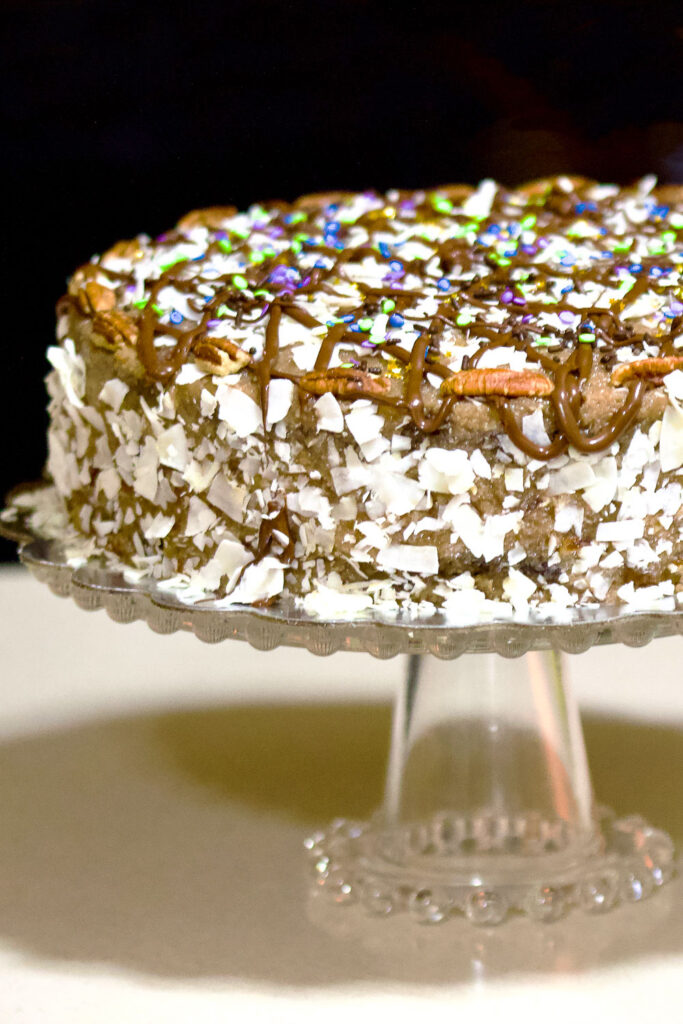 Best homemade German Chocolate Cake that you will fall in love with. This is not your traditional German Chocolate cake. It is less sweet but full of flavors. German Chocolate Cake on cake stand