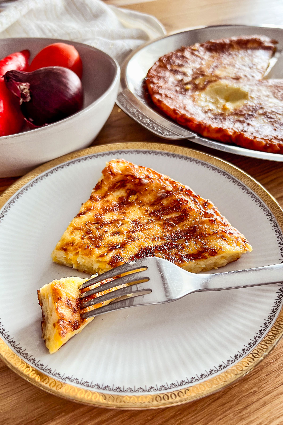 Savory Cheese Pie on round platter with tomatoes and peppers in the background0