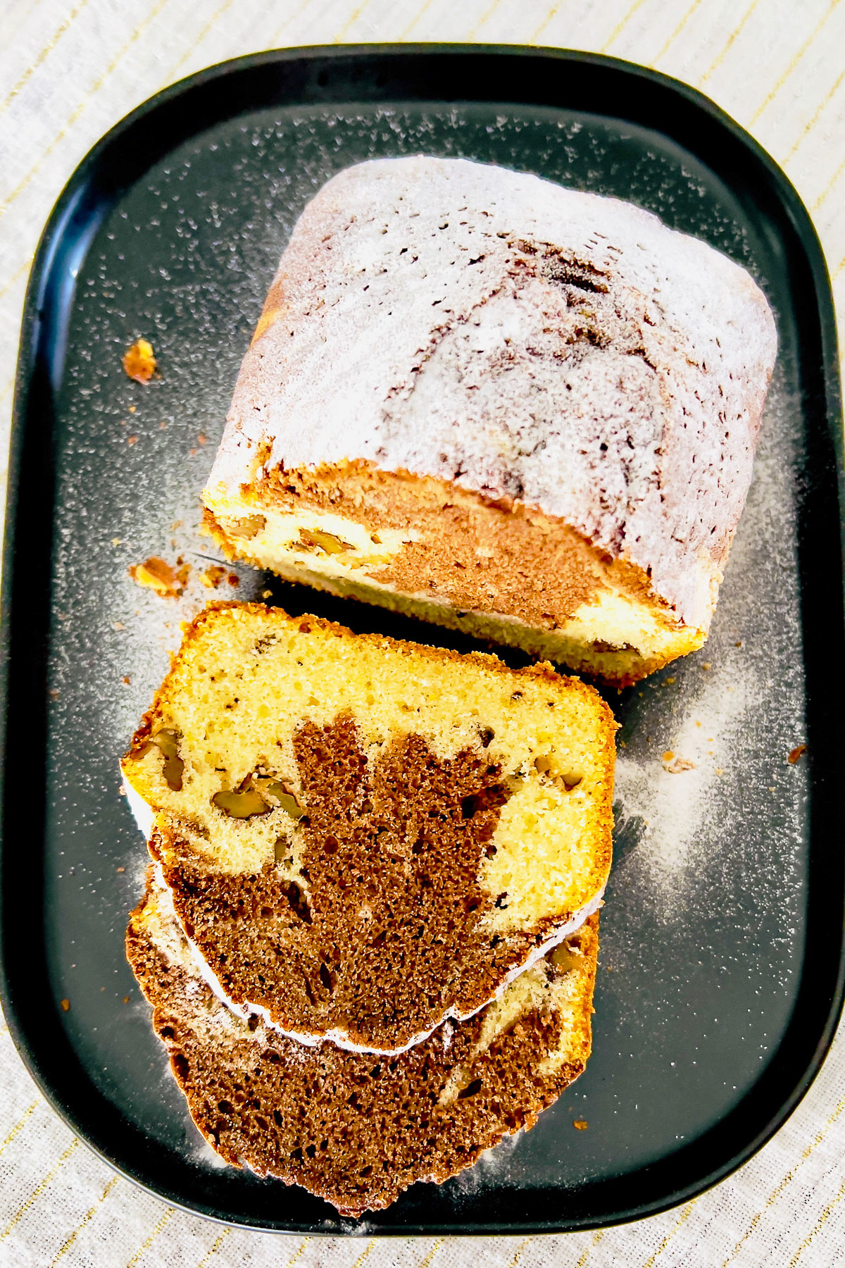 Slices of marble pound cake on black platter.