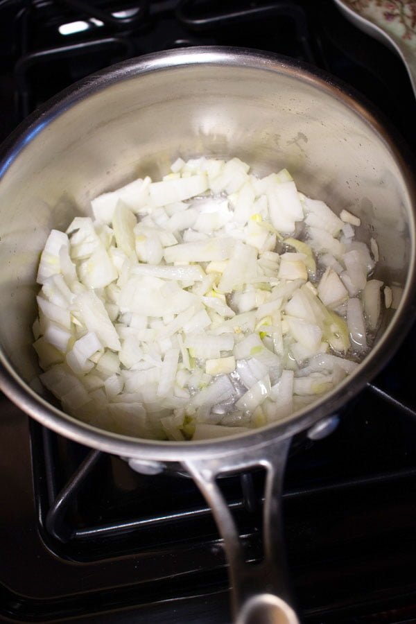 onions cooking in a stainless steel pan