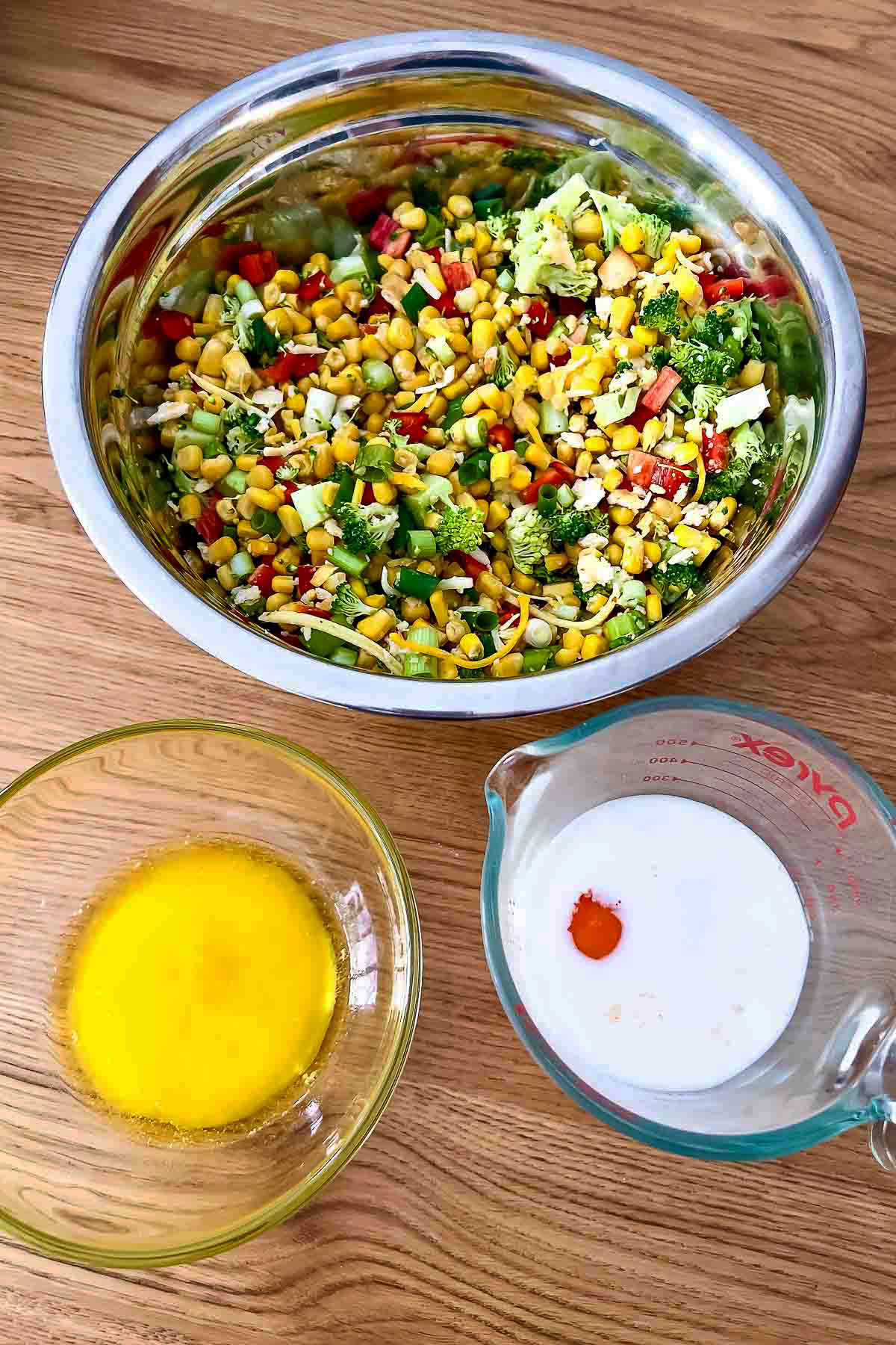 Liquid ingredients for Scalloped Corn next to the chopped vegetables.