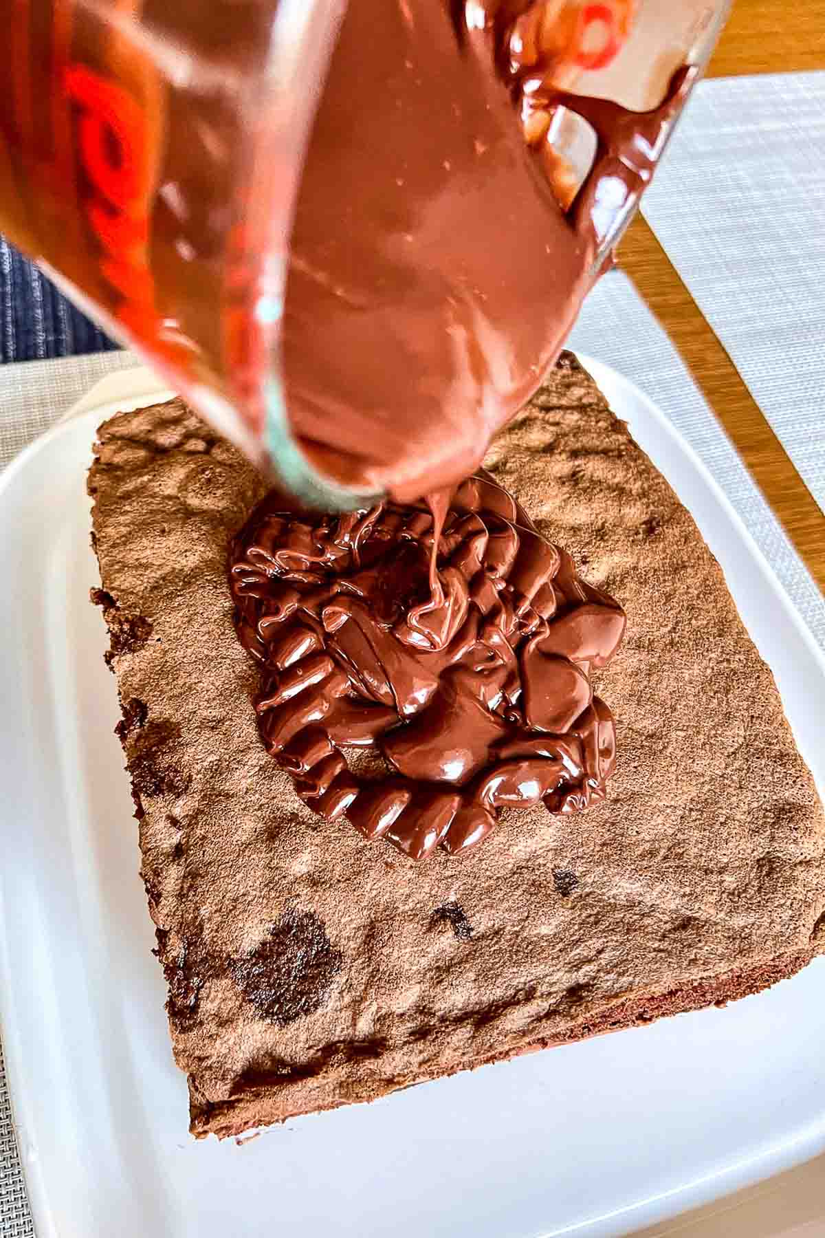Pouring chocolate ganache over the cake.