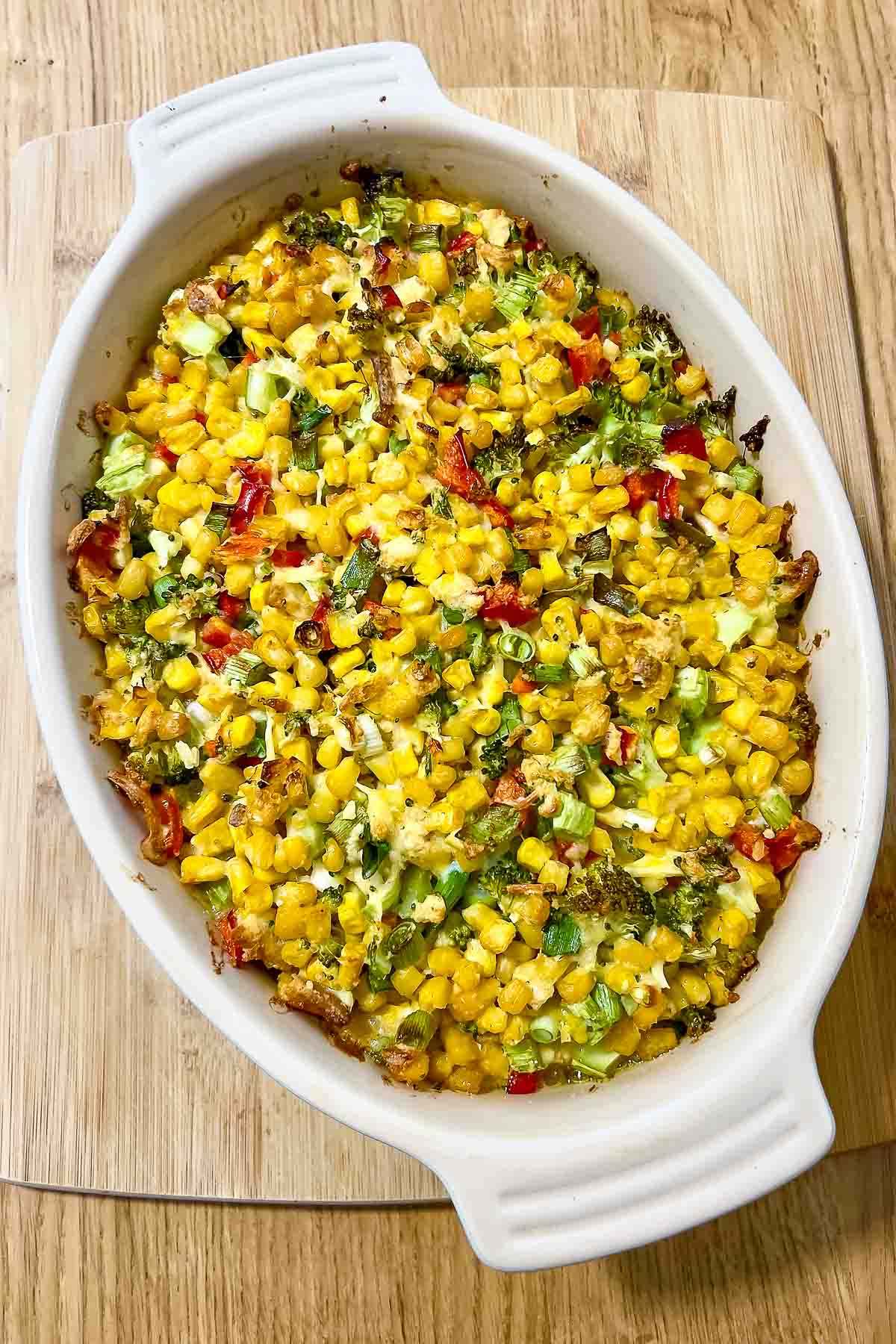 Scalloped Corn Casserole on wooden board.