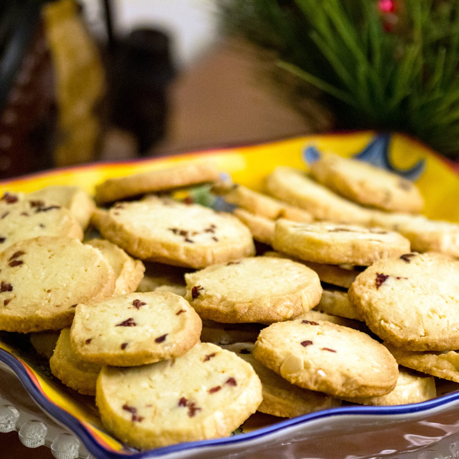 These almond-cranberry shortbread cookies remind us of the holidays. Perfect recipe for potlucks, cookies swap parties and any holiday event. Almond Cranberry Shortbread Cookies on a yellow platter.