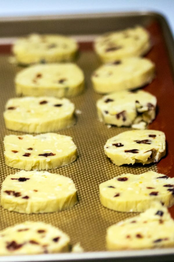 These almond-cranberry shortbread cookies remind us of the holidays. Perfect recipe for potlucks, cookies swap parties and any holiday event. Unbaked almond cranberry shortbread cookies on a baking tray.