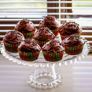 Delicious Chocolate Cupcakes With Chocolate Ganache sitting on a glass cake platter.