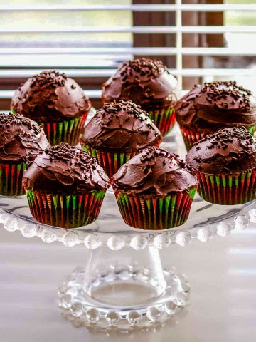Delicious Chocolate Cupcakes With Chocolate Ganache sitting on a glass cake platter.