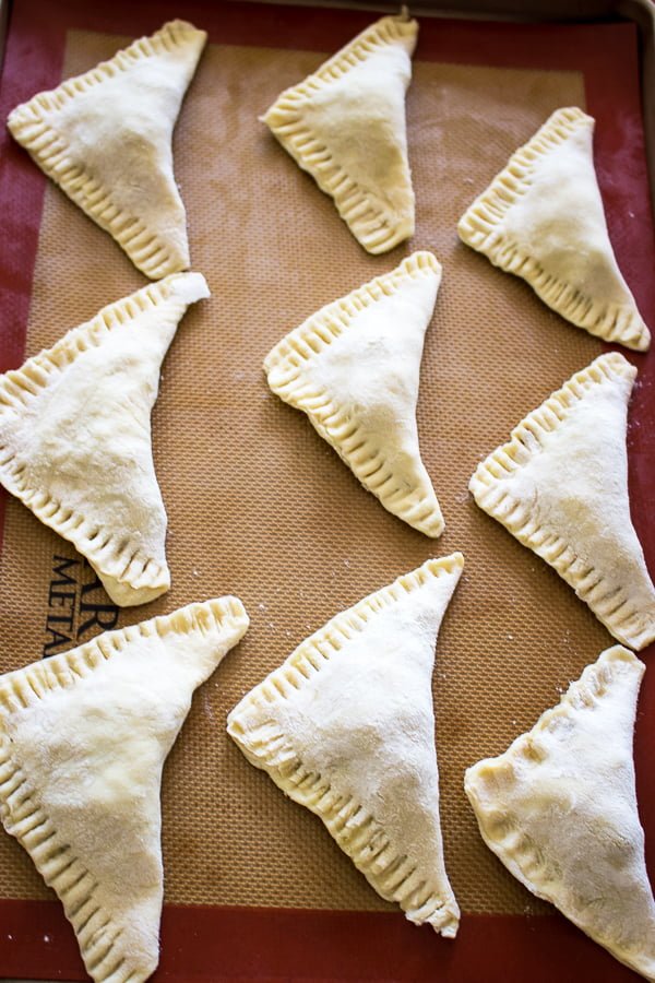 puff pastry triangles filled with cabbage ready for baking on a tray