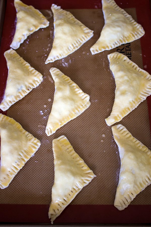 puff pastry triangles filled with cabbage ready for baking on a tray brushed with egg