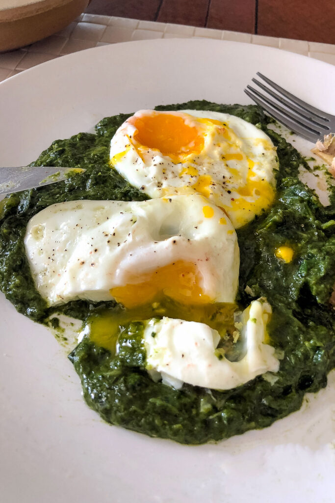 Creamed spinach on plate with fried eggs and fork0