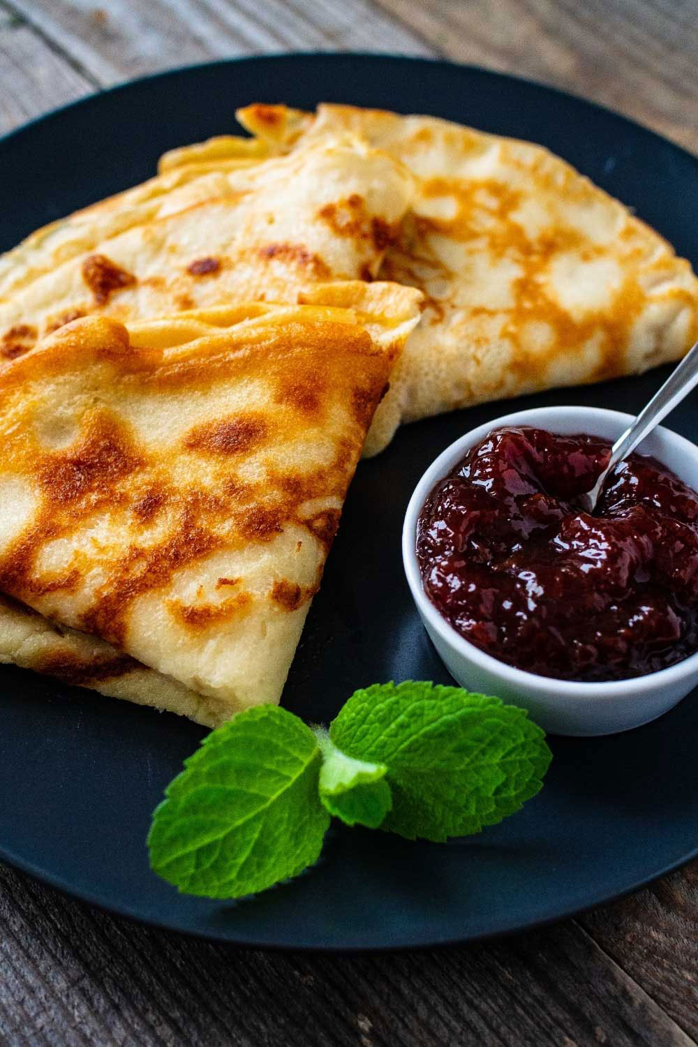 Crepes with jam on a dark plate.