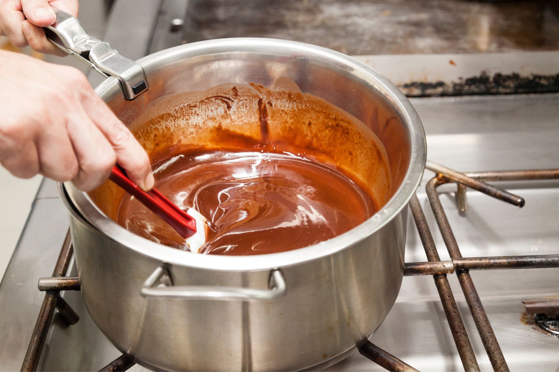 Chocolate syrup in a sauce pan cooking on the stove.