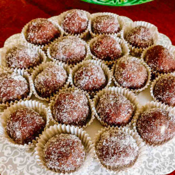 Rum balls in paper candy liners on a platter.