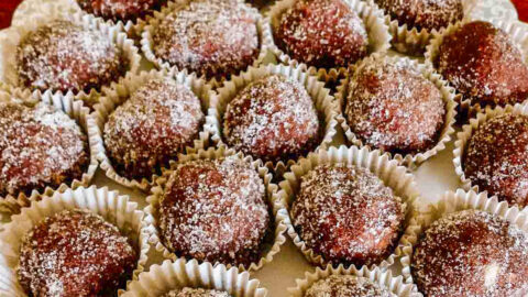 Rum balls in paper candy liners on a platter.