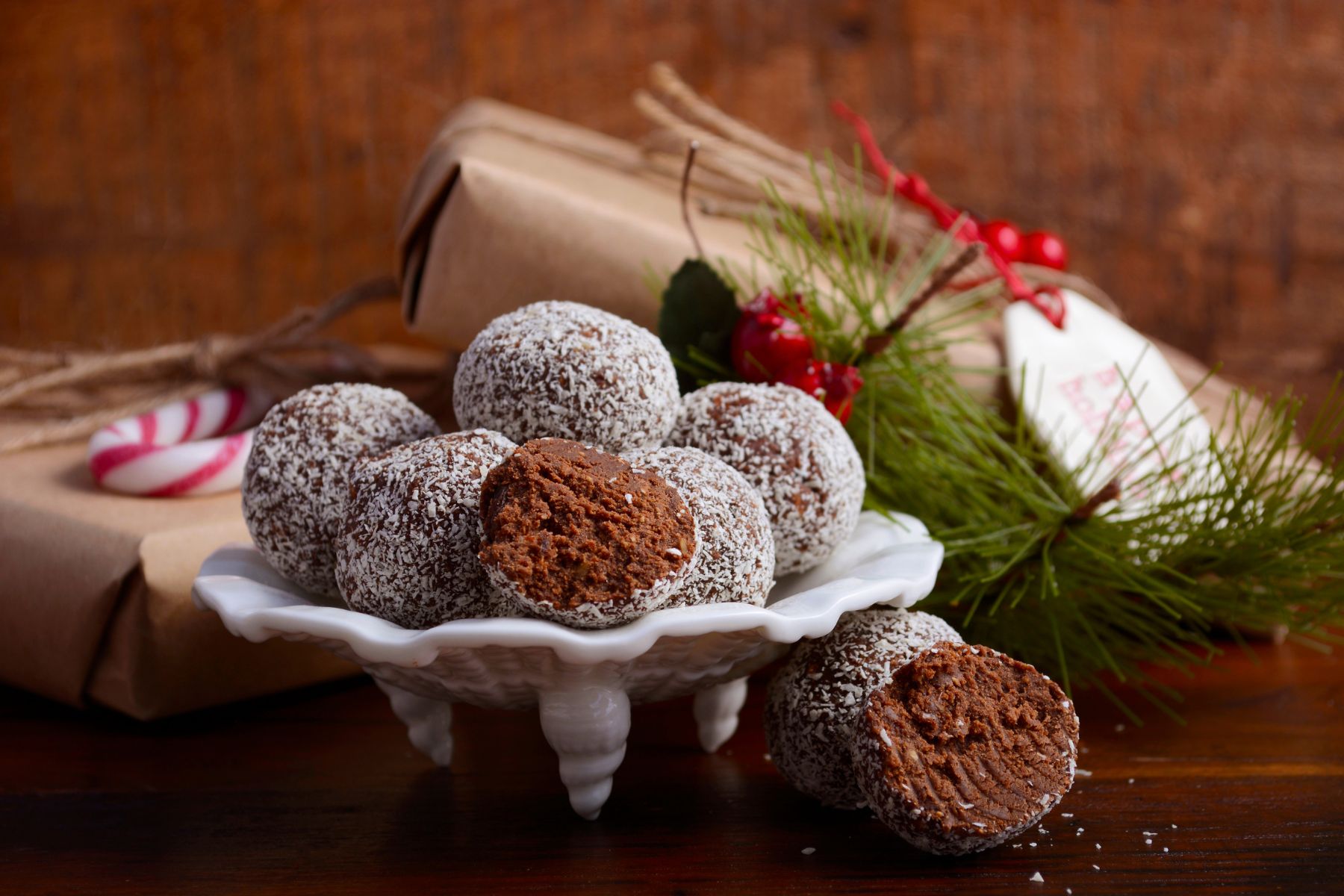Rum balls on a white platter with Christmas decor in the background.