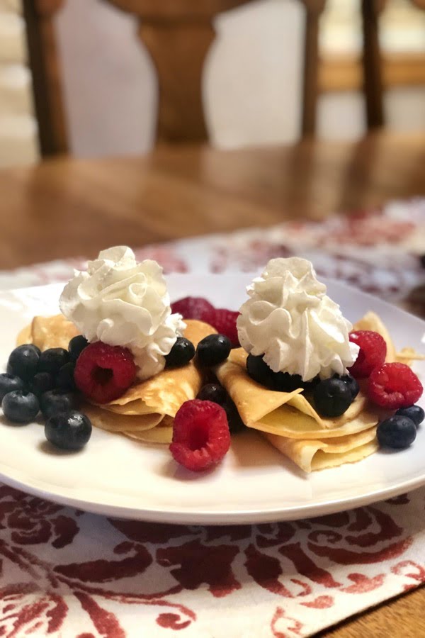 folded crepes with berries and whipped cream