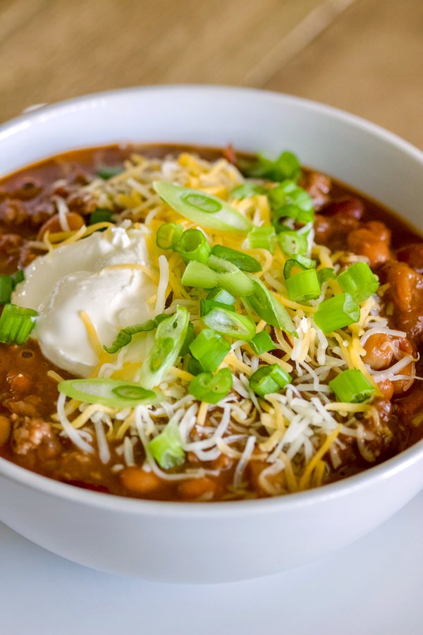 Never had chocolate chipotle chili soup before? Chili soup is a comfort food perfect for the cold nights. When you add smoky chipotle chiles and earthy unsweetened chocolate to it, you add unexpected depth and richness to this hearty chili. Chocolate Chipotle Chili Soup-in a white bowl