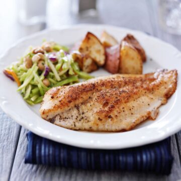 Pan fried fish on white plate square photo