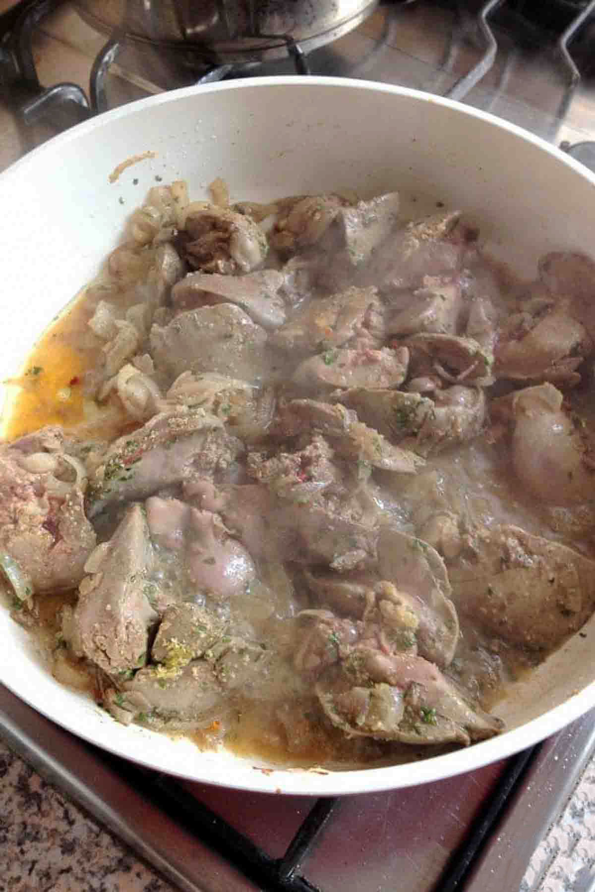 Chicken Livers cooking in a pan with onions and spices.