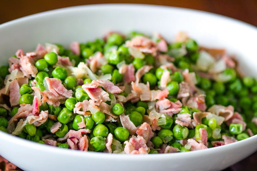 Easy Green Peas With Ham- Spanish recipe- is an easy dish that can be made in no time using fresh or frozen peas. For authenticity, use jamon Serrano. Easy Green Peas With Ham- Spanish recipe- in a white bowl