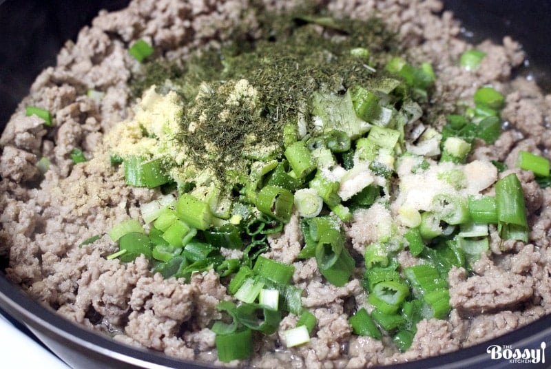ground meat with green onions and seasoning cooking in the pan