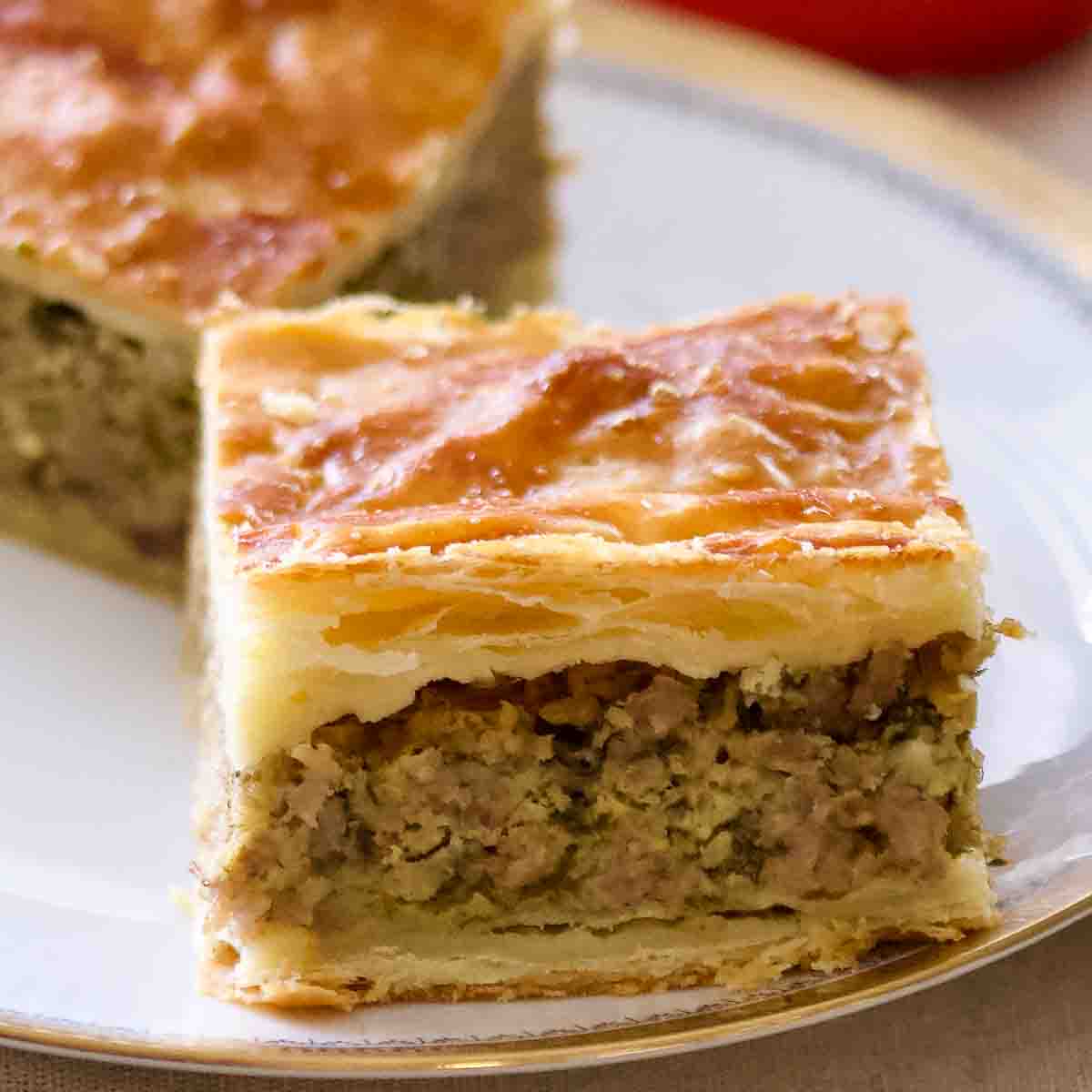 Puff pastry mince meat pie baked sliced on a white plate.