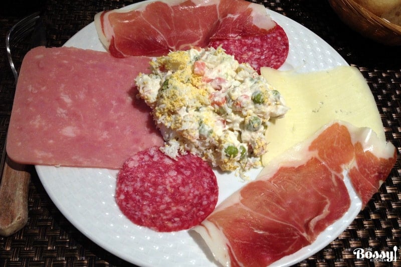 Spanish potato salad (Ensaladilla Rusa) on a platter with hams and cheese