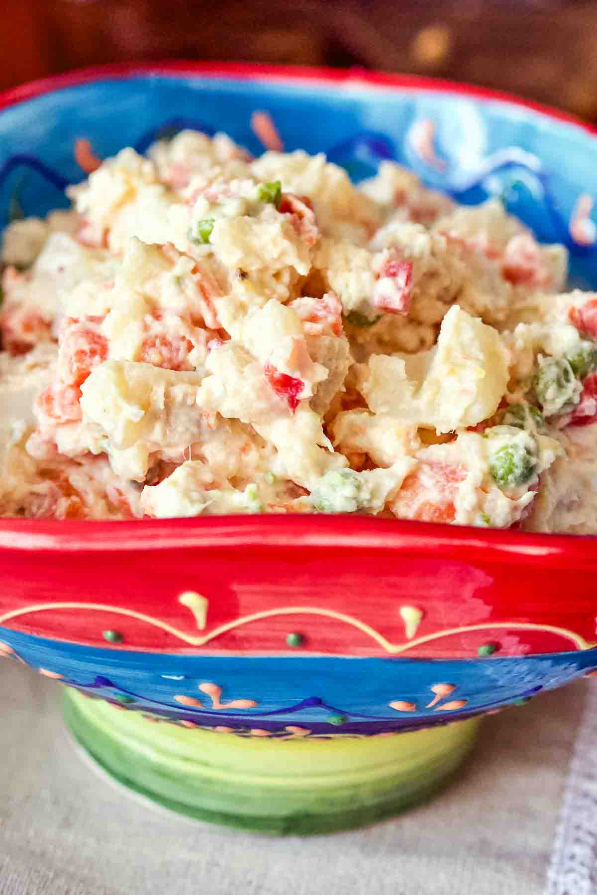 Spanish potato salad (Ensaladilla Rusa) Spanish ensaladilla rusa in a red and blue bowl.