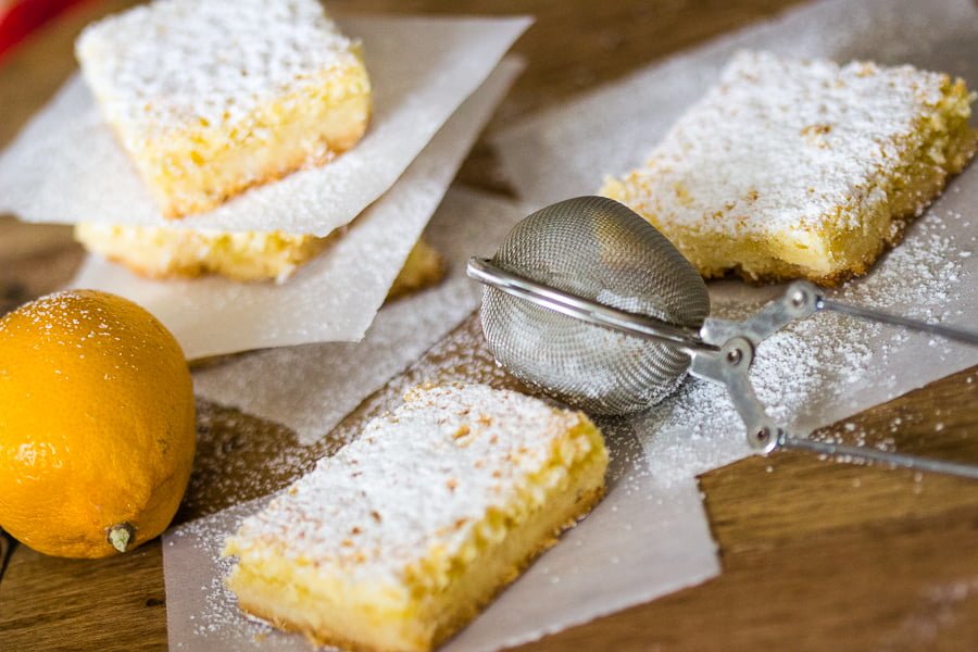 Coconut-Almond Lemon Bars Recipe is a tasty, twisted version of the traditional lemon bars. The combination of coconut, lemon and almond is a perfect one. Coconut-Almond Lemon Bars Recipe - lemon bar squares on parchment paper