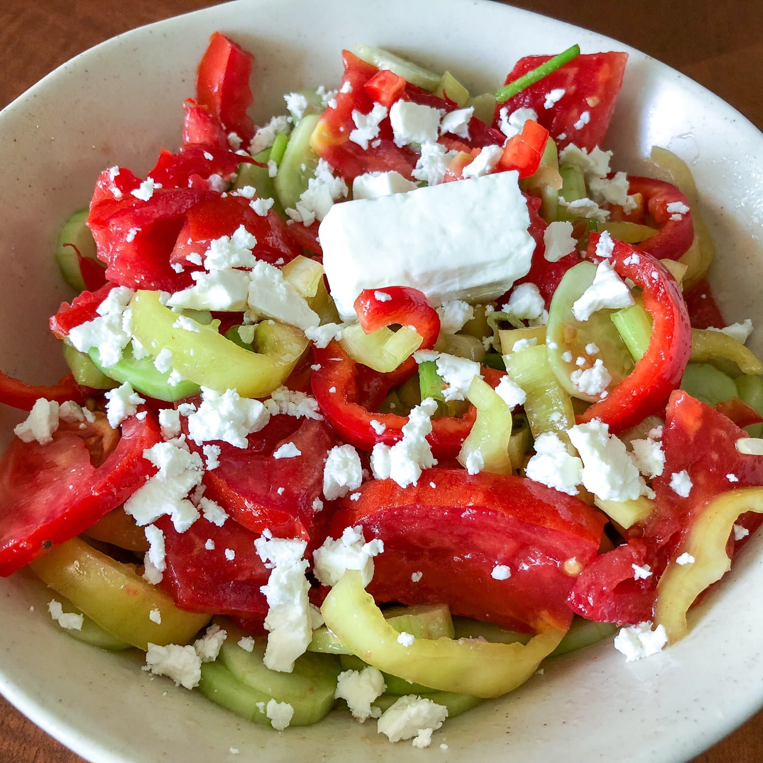 Quick Tomato Cucumber And Pepper Summer Salad is a delicious recipe that uses fresh tomatoes, cucumbers and peppers tossed in vegetable oil and salt. Tomato Cucumber Salad in a white salad bowl with crumbled Feta cheese