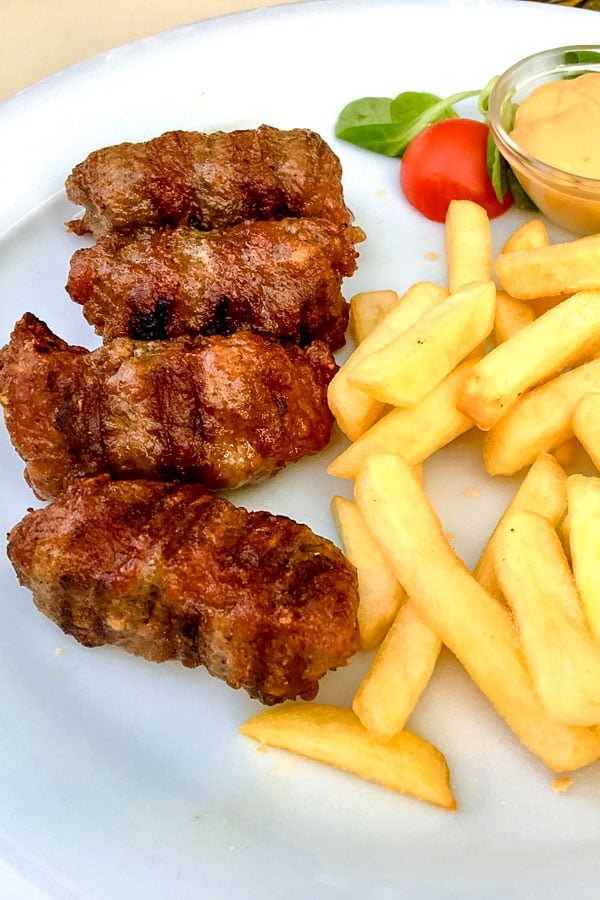 Mititei Romanian Grilled Sausages Mititei Romanian Grilled Sausages served with French Fries and mustard on a white plate