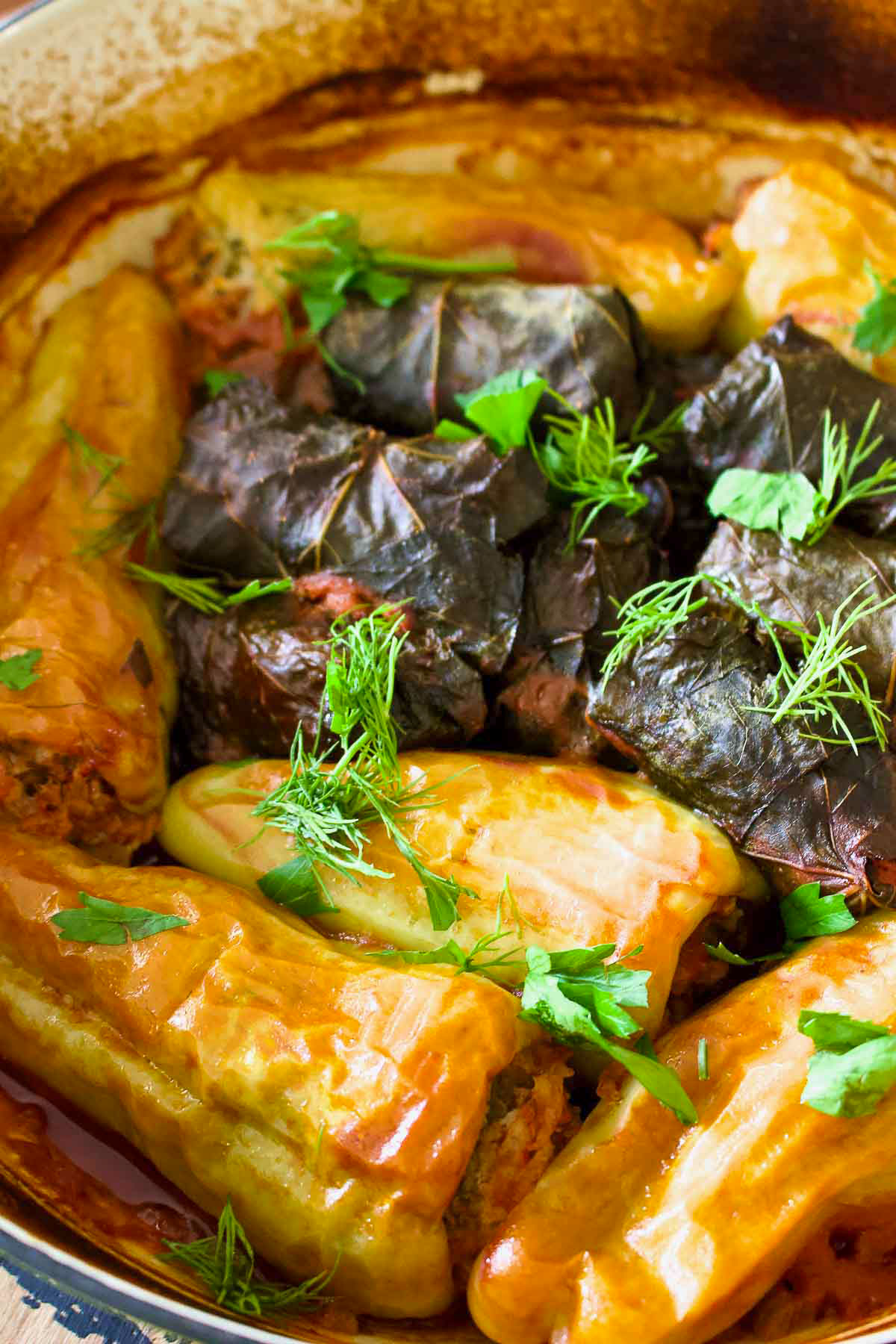 Stuffed peppers (Ardei Umpluti) are a favorite meal in many parts of the world. They are easy to make and delicious. This is a Romanian recipe. Stuffed Peppers in a baking dish with stuffed grape leaves.