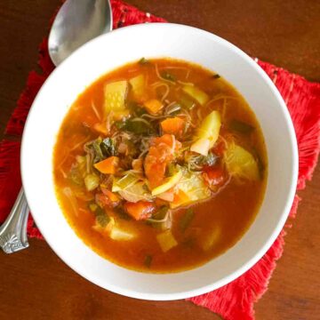 Tomato And Zucchini Soup in a white bowl with spoon.