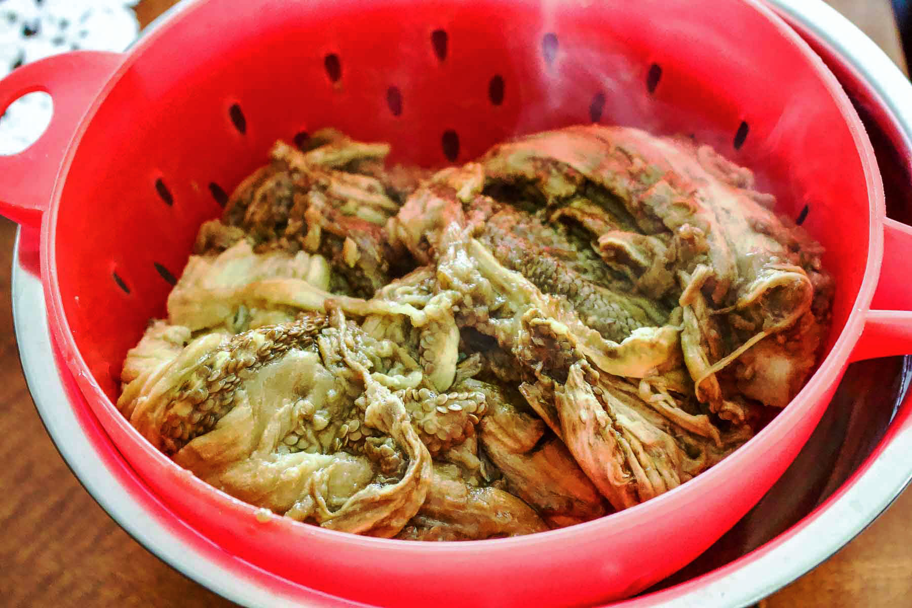 Roasted Eggplant Salad- Romanian Style is a delicious summer salad that can be served on fresh bread with tomatoes and sometimes Feta cheese. Roasted eggplant draining in a sieve.
