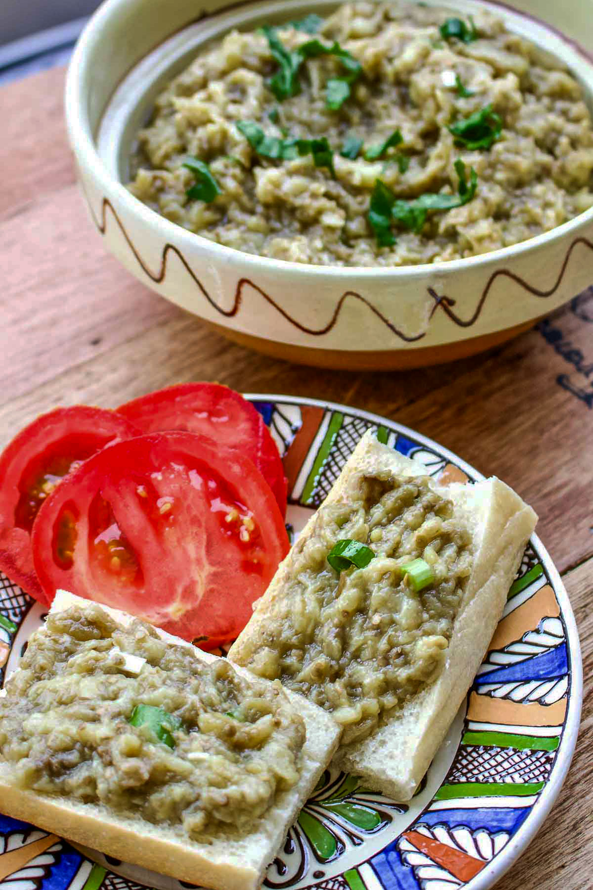 Roasted Eggplant Salad- Romanian Style is a delicious summer salad that can be served on fresh bread with tomatoes and sometimes Feta cheese. Roasted eggplant salad in a bowl with slices of bread.