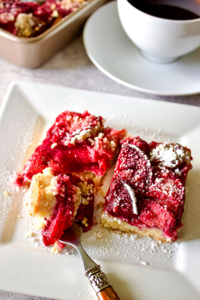 German Plum Kuchen slice with fork on white plate0