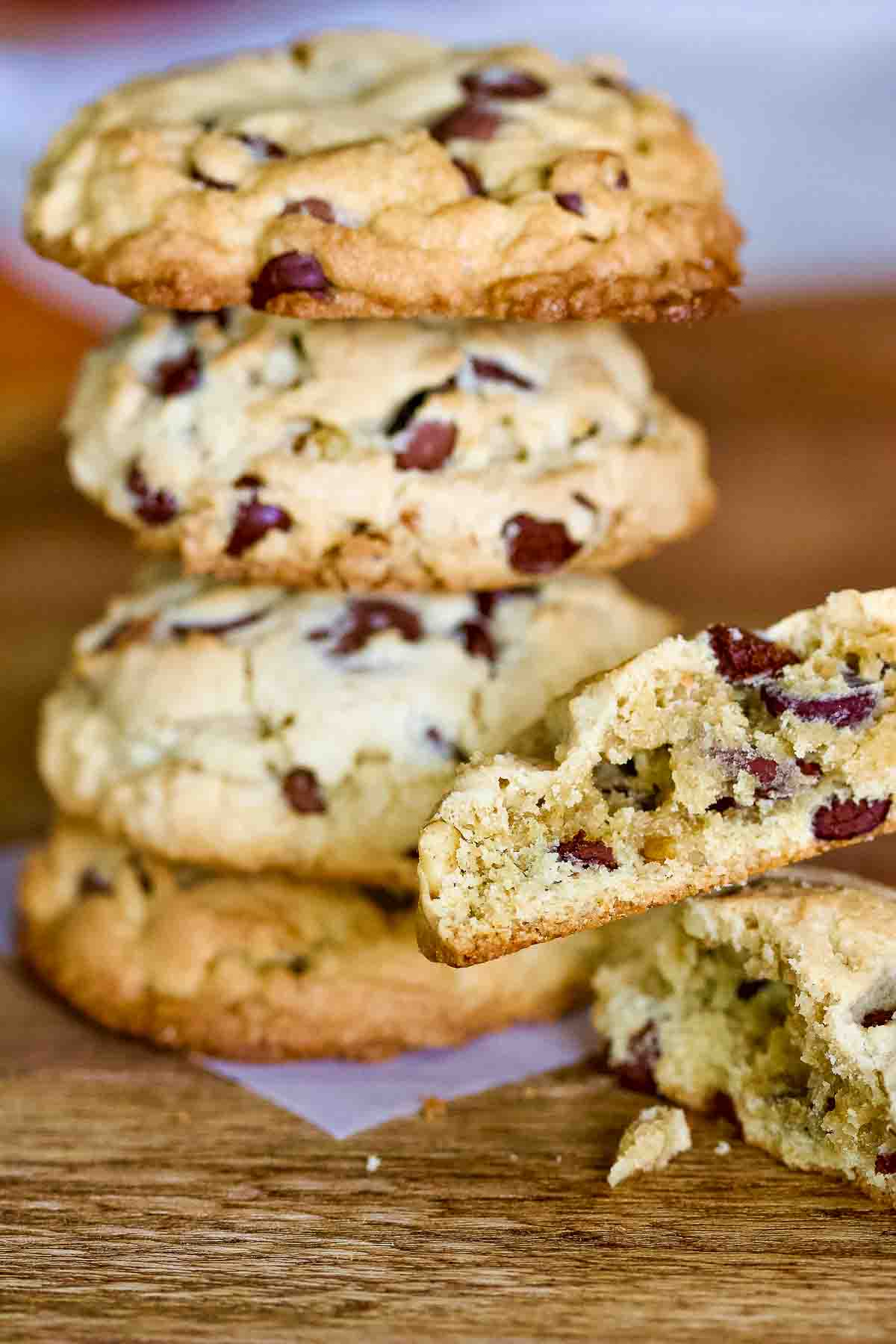 Chocolate chip cookies with walnuts with cookie piece on table.