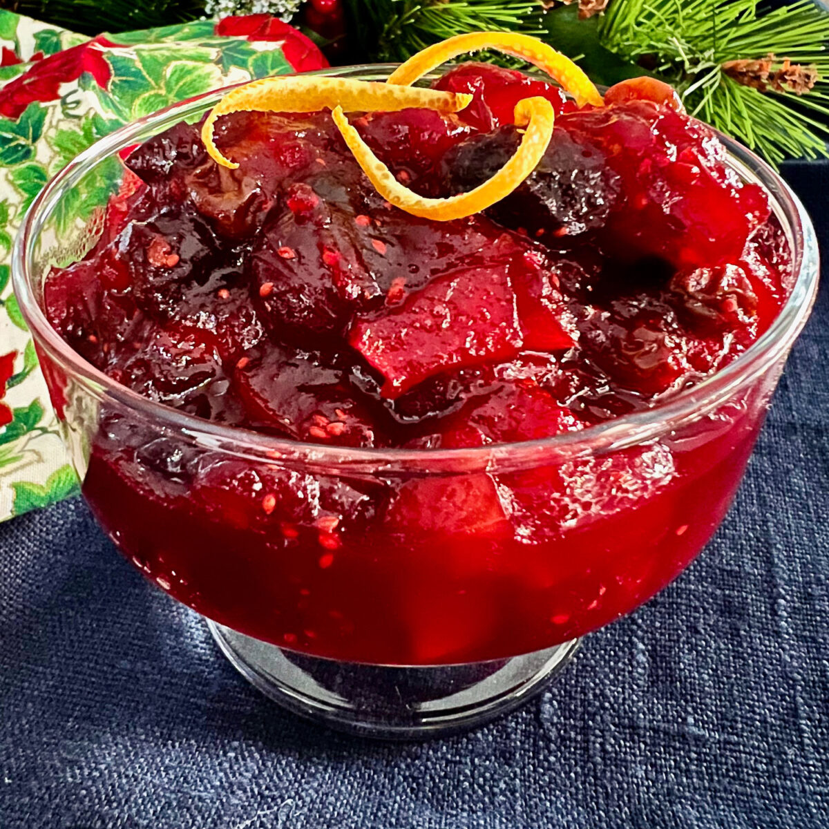 Cranberry Chutney in a glass bowl on the table garnished with a piece of orange zest.