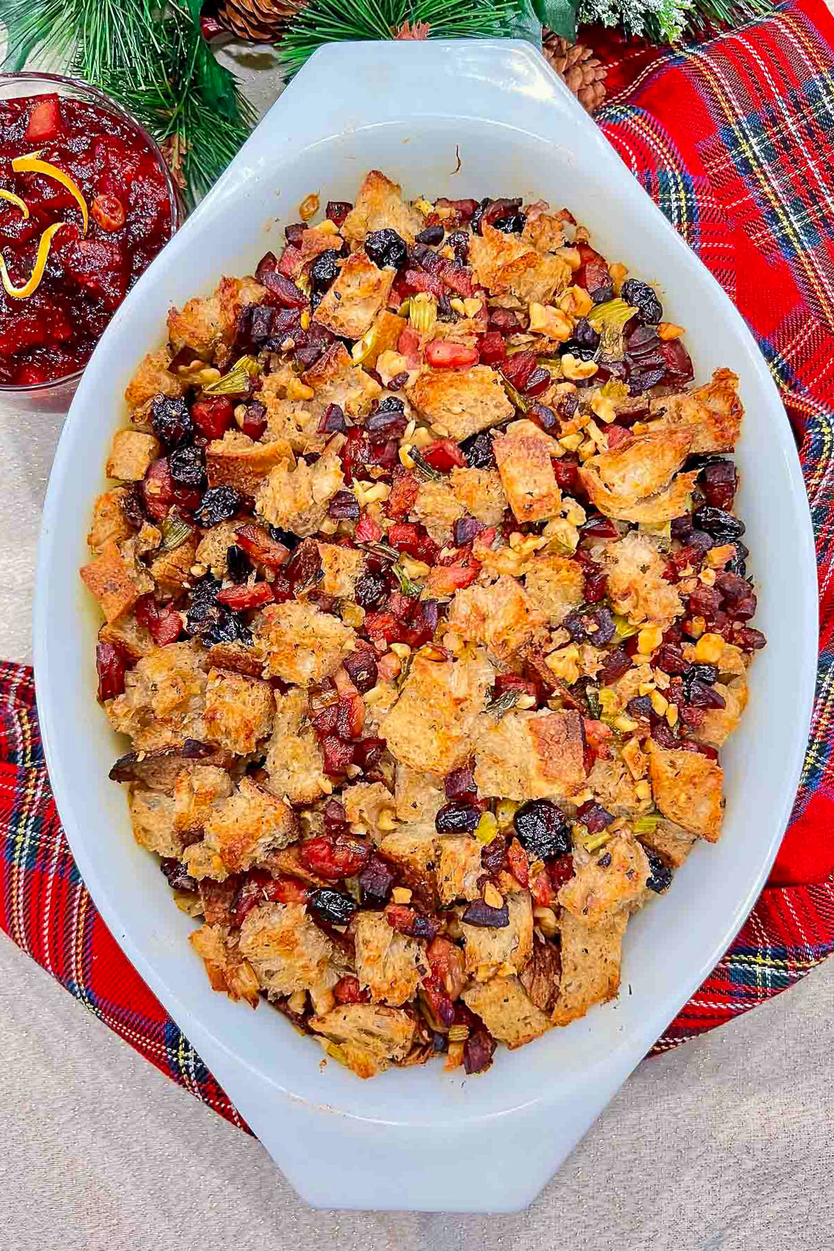 Are you ready for the holidays cooking? Here you have a great, easy sausage, cranberries and walnuts stuffing recipe. Enjoy! Sausage Cranberry Stuffing in a baking dish with cranberry and holidays decorations in the background.