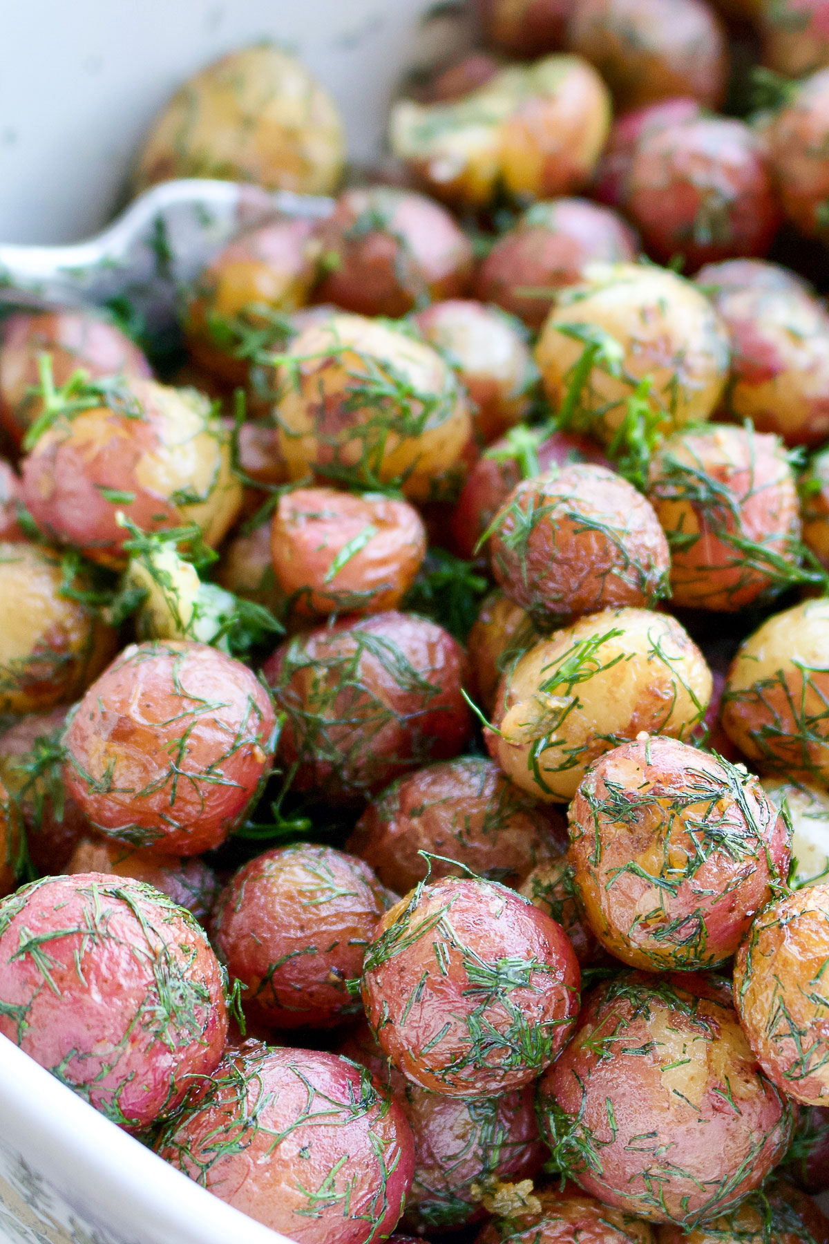 Baby potatoes with butter and dill in a white dish Pinterest photo.