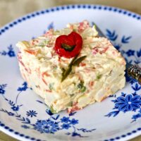 Romanian vegetable salad with mayo serving on a white and blue plate