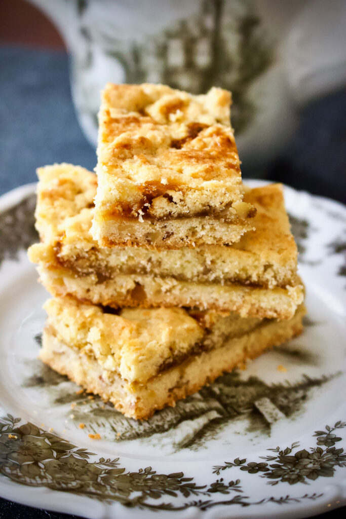 These Czech bars with jam and walnuts are super easy to make and very delicious. An Old World recipe, the bars are buttery, sweet and perfect for any occasion. Stacked Czech bars with jam and walnuts on white and grey plate0