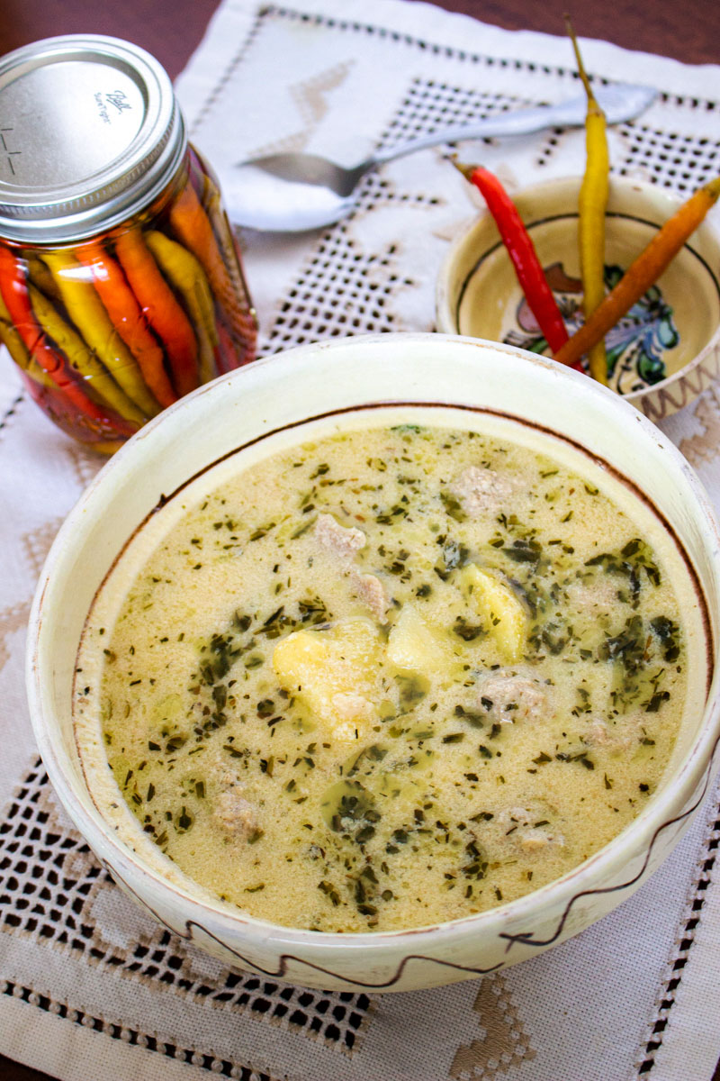 Traditional Saxon Potato Tarragon Soup From Transylvania German Potato Tarragon Soup in a bowl with hot peppers in the background