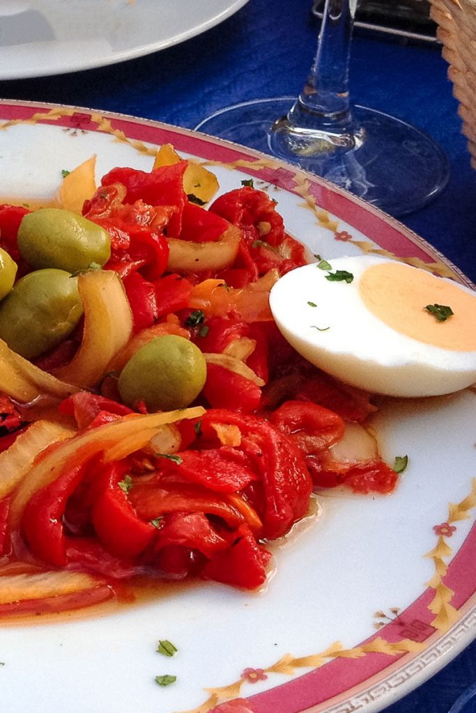 spanish roasted pepper salad on a white plate with hard boiled eggs